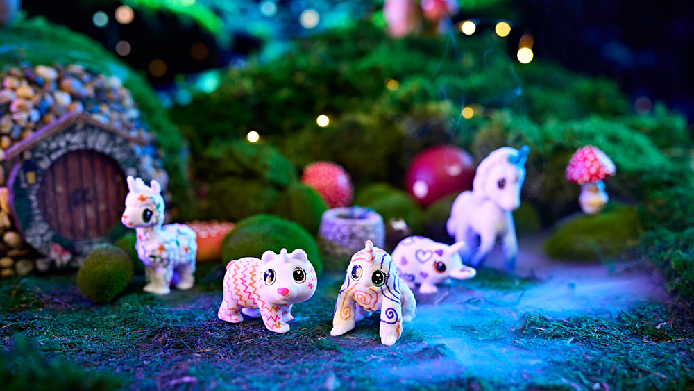 Various decorated uni-creature scribble scrubbies in a fairy garden.